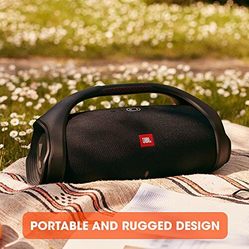 Portable rugged speaker on grass with flowers